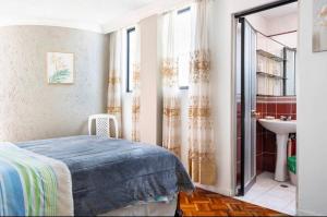 una camera da letto con un letto e un bagno con un lavandino di Suite Lili a Quito