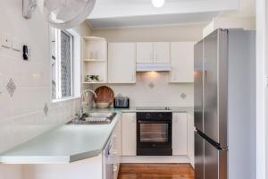 a kitchen with white cabinets and a stainless steel refrigerator at Kaimai House in South West Rocks