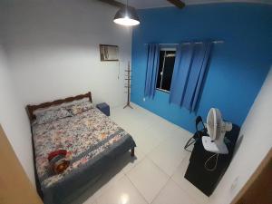 マリカーにあるCabana de férias Itaipuaçuの青い壁のベッド1台、ファンが備わるベッドルーム1室が備わります。