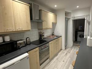 une cuisine avec des placards en bois et des comptoirs noirs dans l'établissement Mornington Crescent Suites, à Londres 23 autres photos