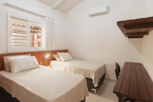 una habitación de hotel con dos camas y una mesa en primeira vista pipa, en Pipa 3 fotos más