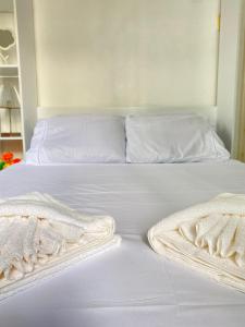 a white bed with white sheets and pillows on it at Melhor Vista de Copacabana! Quarto Casal Privativo em Apartamento Compartilhado in Rio de Janeiro