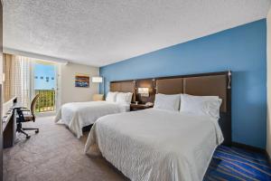 two beds in a hotel room with a blue wall at Holiday Inn Ponce & El Tropical Casino by IHG in Ponce +78 photos
