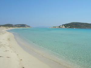 a beach with blue water and mountains in the background at Simosmare Resort in Elafonisos