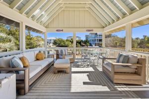 a screened porch with a couch and chairs and a table at High Seas in DeBordieu Colony home by Peace Vacations in Georgetown
