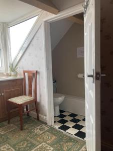 a bathroom with a toilet and a chair and a window at Winston House Guesthouse in Bridlington
