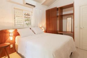 Un dormitorio con una cama blanca y una ventana. en primeira vista pipa, en Pipa