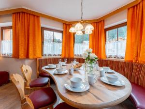 una sala da pranzo con tavolo, sedie e tende arancioni di Löhnersbach a Saalbach Hinterglemm