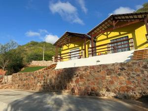 a yellow house on top of a stone wall at Suítes Lampião in Piranhas