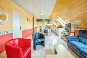 a living room with a blue couch and red chairs at Appartement charmant avec vue sur la mer - Saint-Pol-de-Léon, 60m² in Saint-Pol-de-Léon