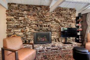 a living room with a stone wall with a fireplace at Waterfall House-Riverfront-Bbq-sleeps Four in Oakhurst