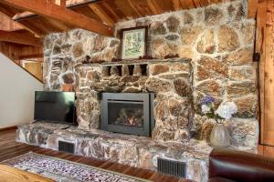 a stone fireplace in a living room with a stone wall at Tranquility House-Riverfront-Fireplace-Sleeps six in Oakhurst