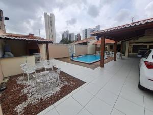 un patio con tavolo e sedie e una piscina di Casa agradável: piscina, churrasqueira e redário. a Natal
