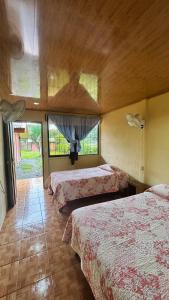 a hotel room with three beds and two windows at Cabinas Caño Negro in Los Chiles