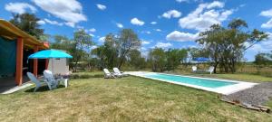 a pool with chairs and an umbrella next to a house at Sapukay in Paraná