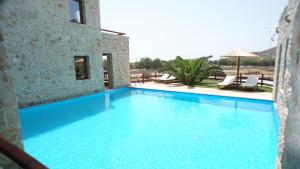 a large blue swimming pool next to a building at Simosmare Resort in Elafonisos