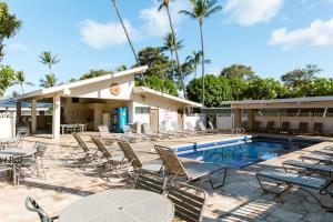 a pool with chairs and tables next to a building at Kihei Akahi A104 in Wailea