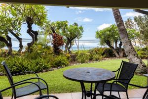 a patio with a table and chairs and the ocean at Kihei Akahi A104 in Wailea