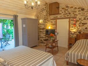 a bedroom with two beds and a tv on a stone wall at Confort et Tranquillité à Blain : Chambre Climatisée, Salle d'Eau Privative, Wifi et Vélos à Disposition - FR-1-306-1253 in Blain