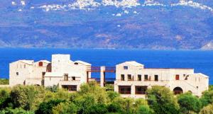 a building on a hill next to a body of water at Simosmare Resort in Elafonisos