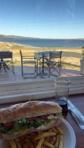 a sandwich and french fries on a plate with a view of the beach at Departamento Lago Los Molinos in Villa Ciudad de America