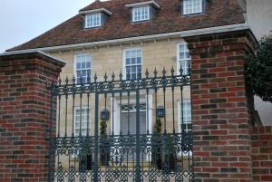 een huis met een zwart hek en een bakstenen gebouw bij Montpellier House in Milton Keynes