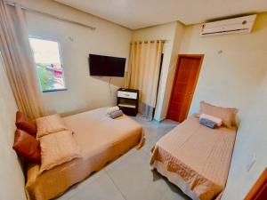 a bedroom with two beds and a flat screen tv at Loft dos sonhos cobertura in Boa Vista