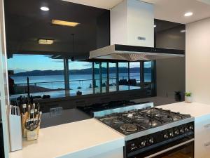 a kitchen with a stove and a view of the ocean at Hobart Bay Sunrise House--Rare Aurora Viewing Opportunities in Hobart