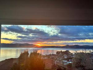 a view of a sunset from a window at Hobart Bay Sunrise House--Rare Aurora Viewing Opportunities in Hobart