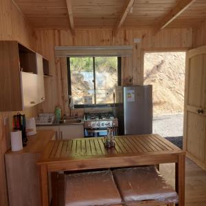 a kitchen with a refrigerator and a table in a cabin at Cabaña Frente al Mar in Licantén