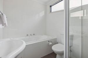 y baño blanco con aseo, bañera y lavamanos. en Apres 9, en Jindabyne