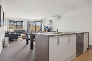 Una cocina con gabinetes blancos y una sala de estar. en Apres 9, en Jindabyne 21 fotos más