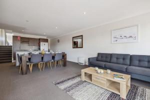 Una sala de estar con un sofá azul y una mesa. en Apres 9, en Jindabyne