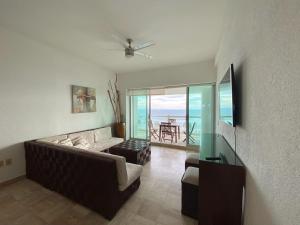 a living room with a couch and a view of the ocean at Mayan Playa Departamento Uxmal in Acapulco
