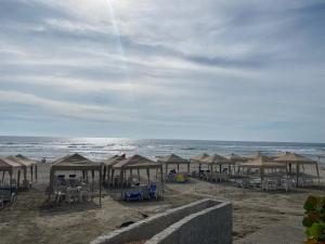 a beach with many umbrellas and chairs and the ocean at Mayan Playa Departamento Uxmal in Acapulco