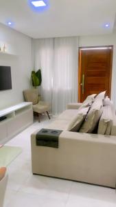 a white bedroom with a large bed and a tv at Casa pra temporada 3 quartos 10 km de Cabo frio in São Pedro da Aldeia