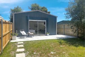 a gray shed with a chair in a yard at Two Gums Cottage in St Helens