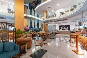 a lobby with a restaurant with tables and chairs at The Blue Mavi Hotel in Chalong 
