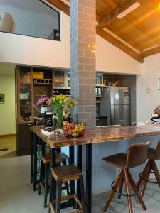 a large kitchen with a large wooden counter and stools at Casa de Campo Completa Cabanas Monte Sierra in Urupema