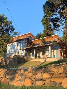 a house sitting on top of a rock wall at Casa de Campo Completa Cabanas Monte Sierra in Urupema