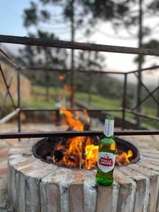 a bottle of beer sitting in front of a fire at Casa de Campo Completa Cabanas Monte Sierra in Urupema