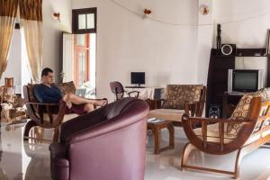 a man sitting on a couch in a living room at Lagoonvilla hotel in Ambalangoda
