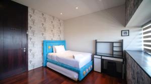 a bedroom with a blue bed and a television at Spacious and Restful 2BR at Sumatra36 Apartment By Travelio in Surabaya +25 photos