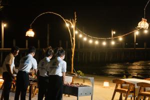 a group of people standing around a table with food at SoonNoeng Resort in Koh Rong Sanloem