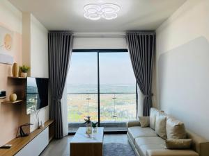 a living room with a couch and a large window at May Homes - Masterise Centre Point Vinhomes Grand Park in Long Bình