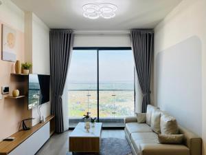 a living room with a couch and a large window at May Homes - Masterise Centre Point Vinhomes Grand Park in Long Bình +32 photos