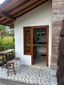 a patio with a table and two stools in front of a house at Ubud Leke-Leke Guesthouse - Rumah Kayu in Gianyar +1 photo