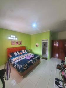 a bedroom with a bed and green walls at Villa PakDe Hulu Cai in Ciawi