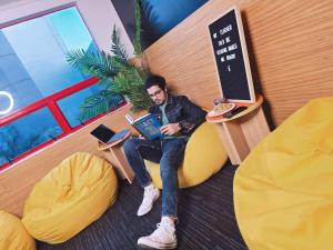 Un uomo seduto su una sedia con un libro di United Auckland ad Auckland