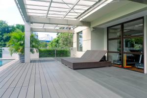 a patio with a couch on a wooden deck at Apartment 3BR with River View in City Center at Sumatra36 Surabaya By Travelio in Surabaya